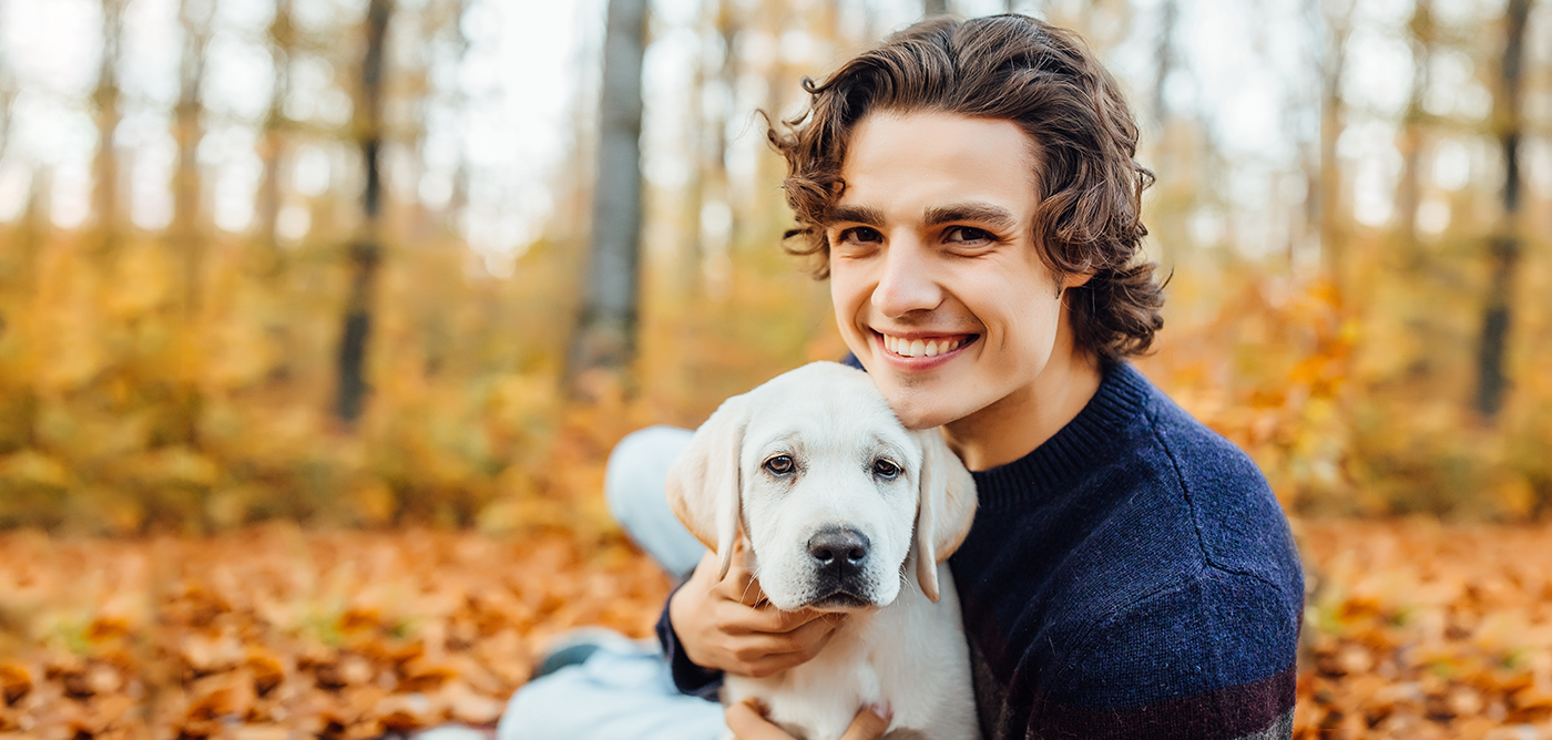 Photo of happyman and his labrador playing together in the autumn forest